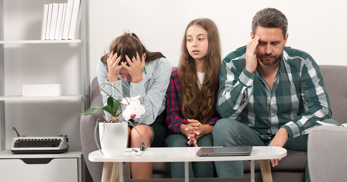 Familia sentada en un sofá mostrando tensión y carga emocional, representando el impacto de no estar en el propio lugar dentro de los vínculos.